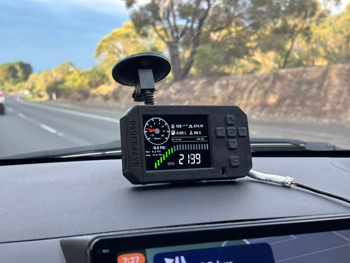 The first Anvil prototype on the dash showing a boost gauge and engine speed, bushland beside the highway